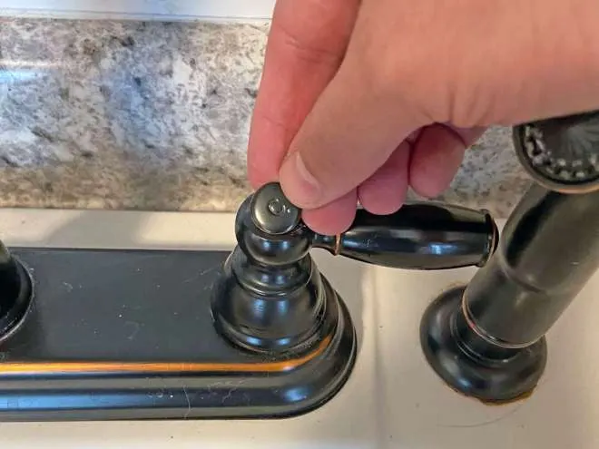 step-by-step instructional guide on how to tighten the temperature handles on a sink  In this case, we are looking at an oil rubbed faucet on a utility sink
